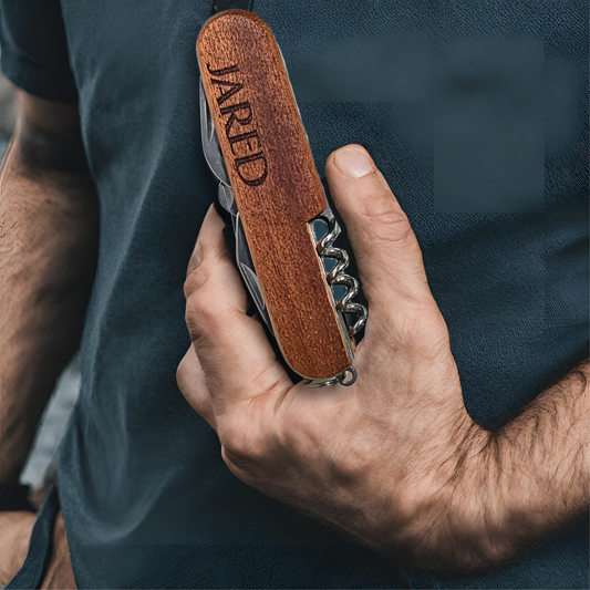 A person in a dark shirt holds The Ultimate Gift for Him: Versatile 8-Function Pocket Tool, featuring a wooden handle with the name Jared engraved. This multi-tool includes metal components like a corkscrew.