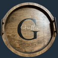 Load image into Gallery viewer, The Boho Bliss: Custom Round Serving Tray features a dark wood finish with handles, a large G, and Griffin in white script, making it a charming, rustic addition to any home.