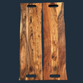 Load image into Gallery viewer, Two rectangular acacia wood Sophisticated Dining: Engraved Grazing Boards feature handles and showcase rich grain patterns. The engraved logo near a handle adds elegance, making them a perfect entertaining accessory against a dark background.