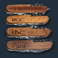 Load image into Gallery viewer, Four The Ultimate Gift for Him wooden pocket knives, personalized with engravings SJG, RGC, LBC, and CADE, feature a polished handle containing an 8-function multi-tool. Their craftsmanship stands out against a dark background.