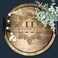 Load image into Gallery viewer, The Boho Bliss: Custom Round Serving Tray for Effortless Entertaining showcases intricate carved designs with the number 11 and Habits, a tassel with black and white beads, a wooden house charm on the left, and a small potted plant on the right.