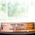 Load image into Gallery viewer, The Sophisticated Dining: Engraved Grazing Board, made from rich acacia wood, features the engraving: Myers Kitchen. The best of times are always found when family and friends gather round, and is elegantly displayed on a table with a blurred outdoor backdrop.