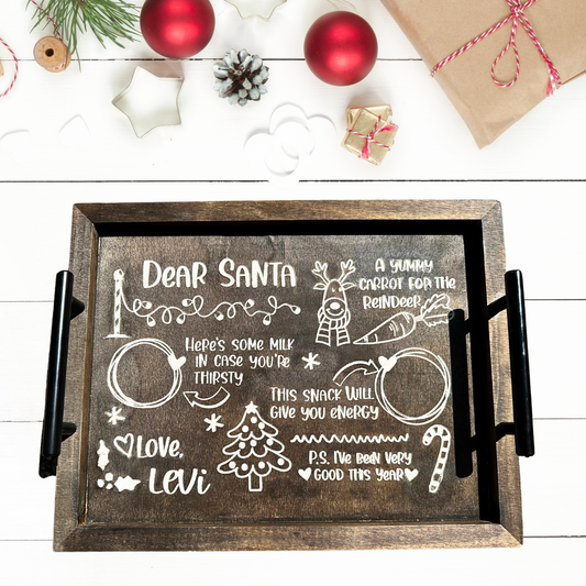 The Cookies for Santa Serving Tray, featuring chalkboard-style writing, reads: Dear Santa, heres milk in case youre thirsty, a yummy carrot for the reindeer. This snack will give you energy. P.S. I’ve been very good this year! Love, Levi. Perfect for Christmas Eve decor.